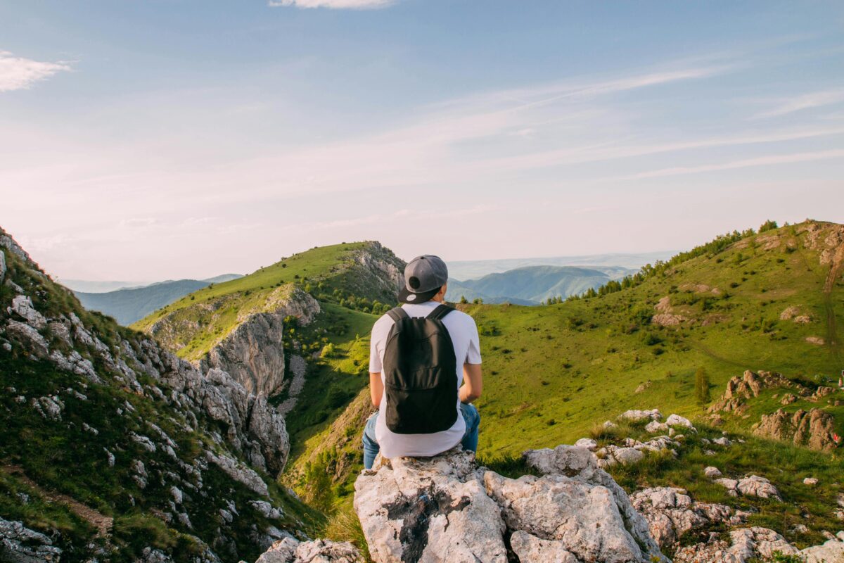 Man sitting on rocks with a scenic mountain view in Rimetea, Romania, perfect for adventurers.
