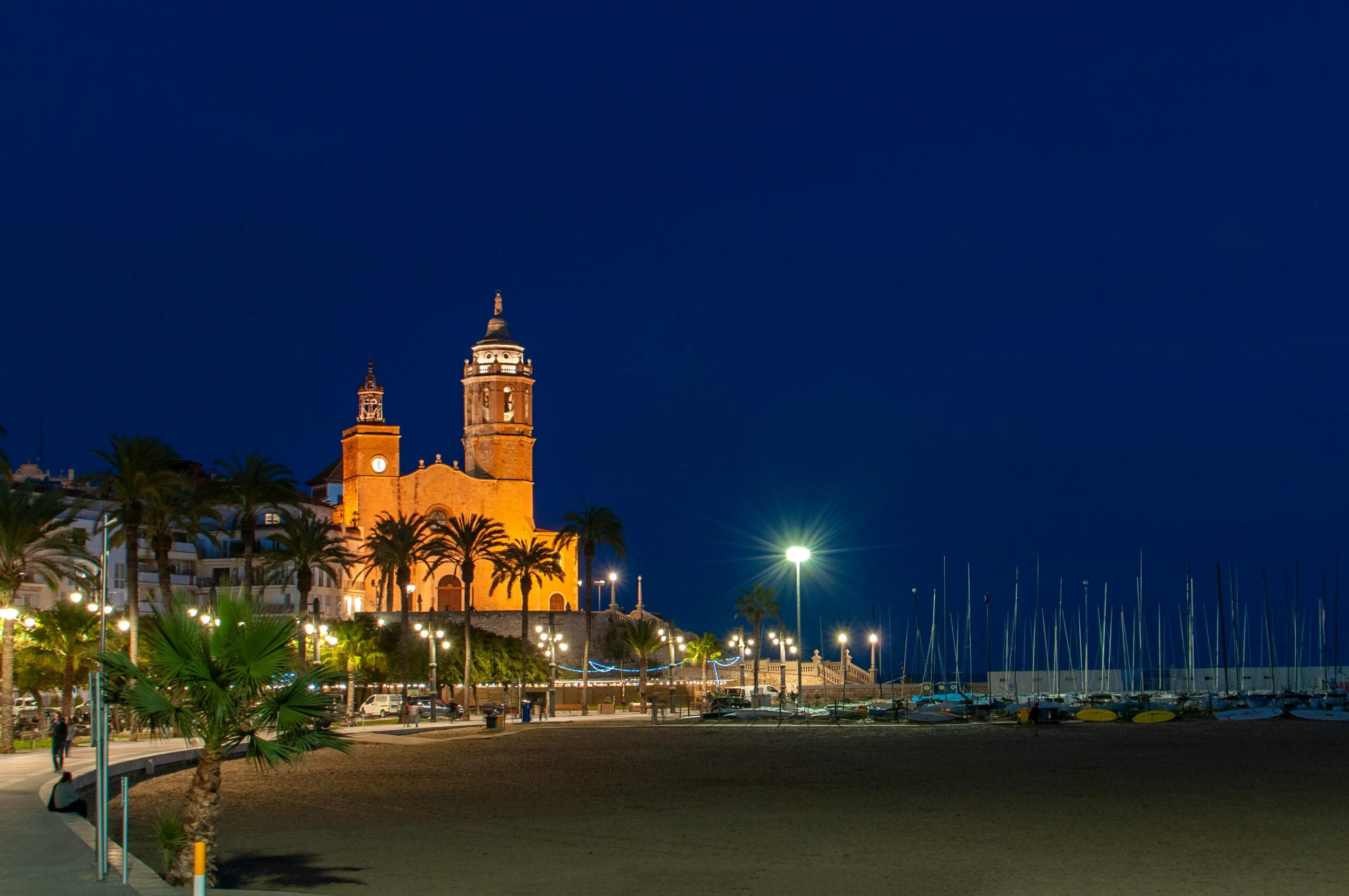 Capture of the illuminated church and promenade by the beach in Sitges, Spain at night.